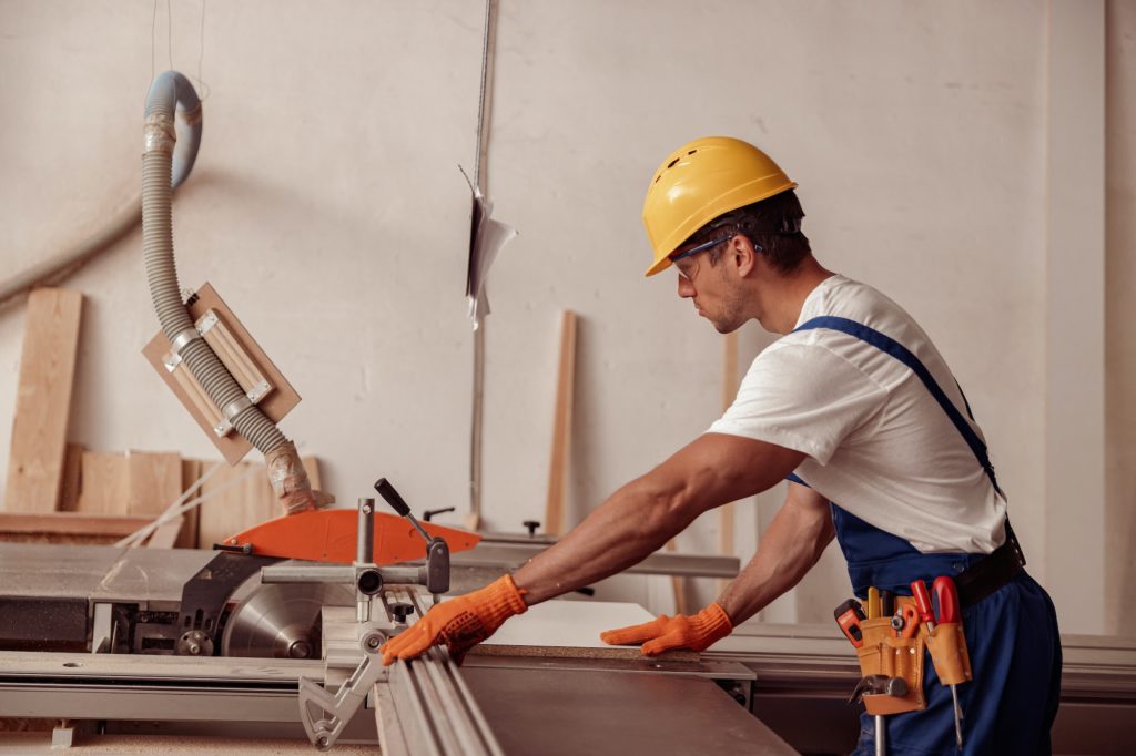 Male builder using woodworking machine in workshop